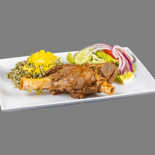 A ZK Grill lamb shank with green rice, saffron rice, and a side salad on a white plate.