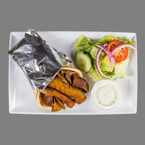 ZK Grill's Mediterranean gyro platter with meat, a side salad, and dressing on a white plate.